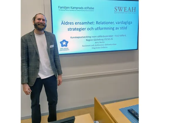 Man gör en presentation bredvid en stor skärm