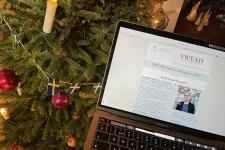Nyhetsbrev på bärbar dator med julgran i bakgrunden.