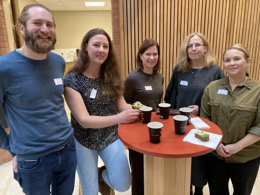 Fem doktorander fikar vid ett ståbord