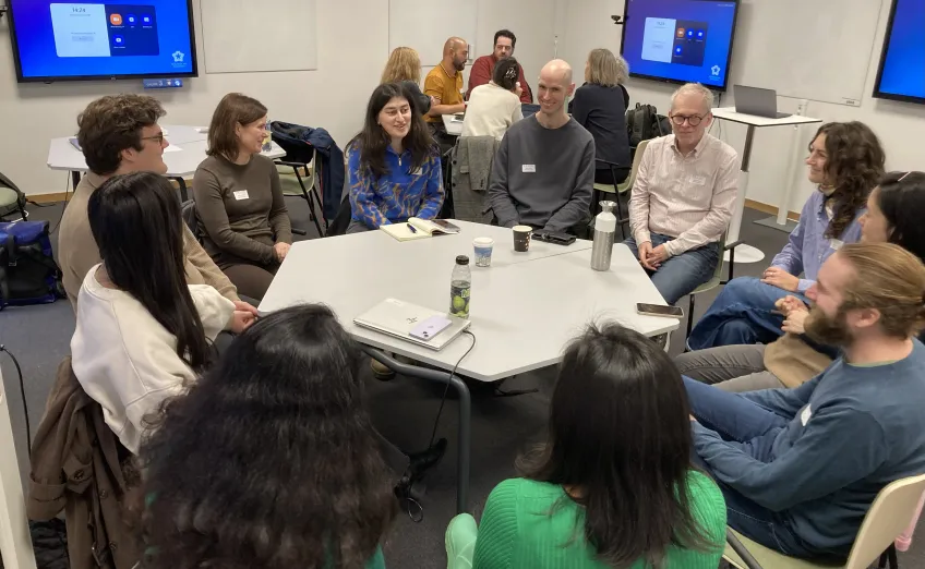 Doktorander och kursledare sitter tillsammans runt ett runt bord.